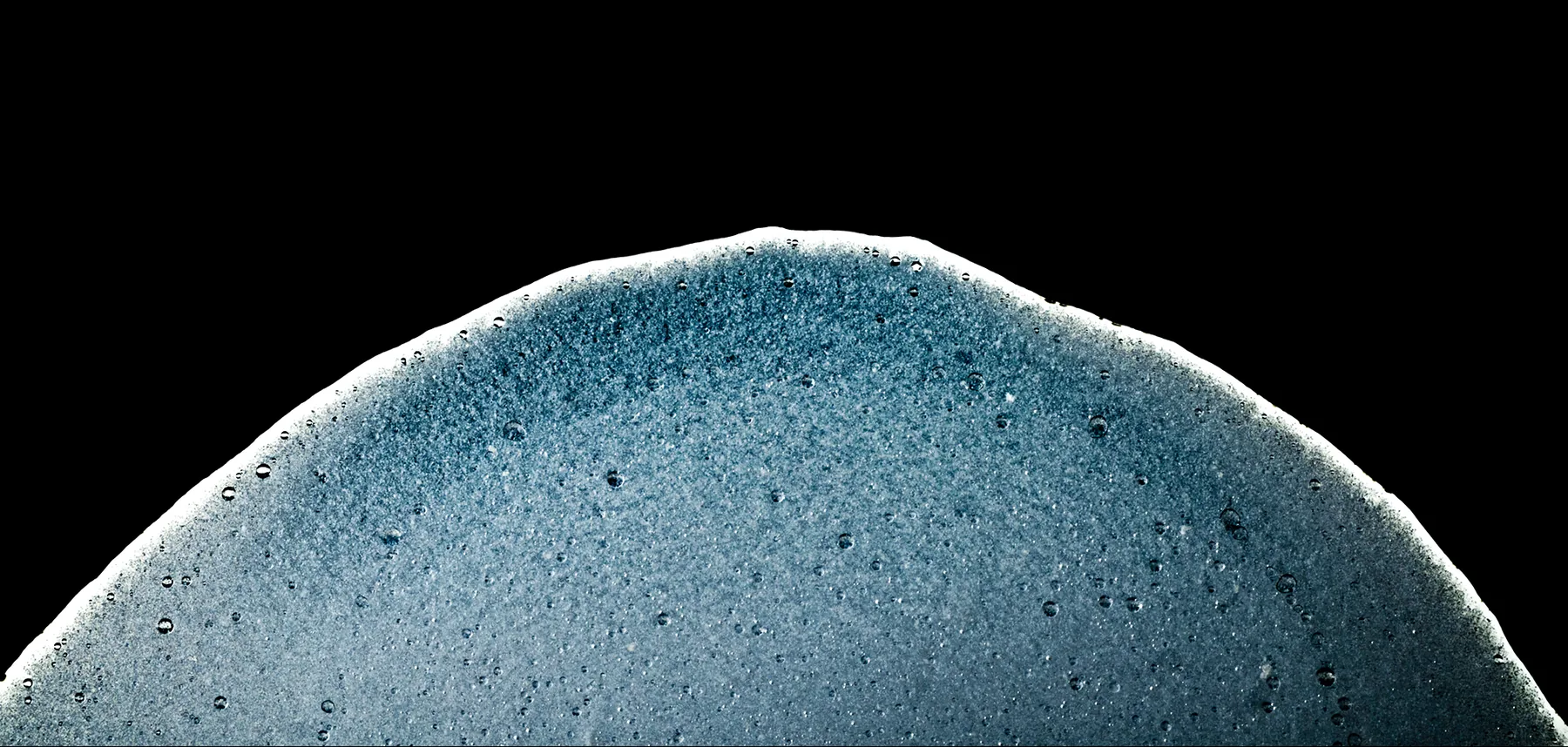 Macro photograph of a blue mineral foam dome against black